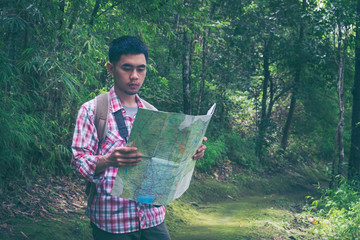 Hiker man looking to map standing in tropical forest