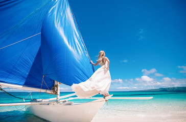 beautiful bride on wedding day ready for travel by sail boat.