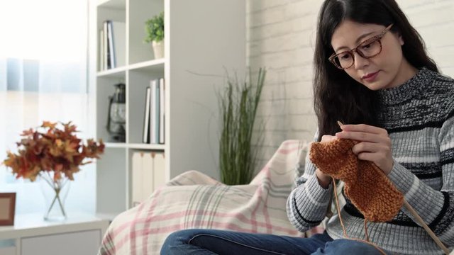 Asian woman sitting on the sofa and knitting