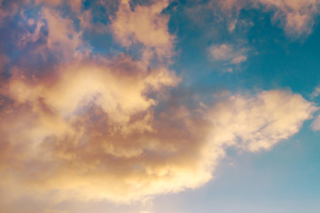 Bright yellow clouds on the blue sky at sunset or sunrise