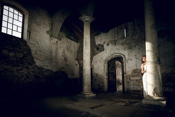 Mujer con vestido blanco en el templo antiguo iluminada por la luz del sol al atardecer