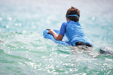 Boy swimming or playing with waves, having fun in the blue sea water, Water games, childhood, vacation, holiday.