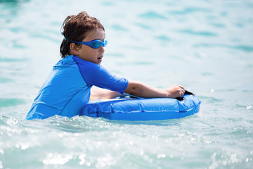 Boy swimming or playing with waves, having fun in the blue sea water, Water games, childhood, vacation, holiday.
