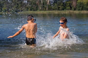 Kids jumping, swimming and playing with water in a polish lake, summer holiday in Greater Poland. Leisure - boys point of view. Beautiful childhood.