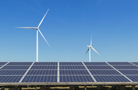    solar cells with wind turbines generating electricity in hybrid power plant systems station on blue sky background alternative renewable energy from nature  Ecology concept.   