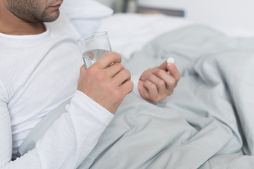 Sick man holding pill and glass
