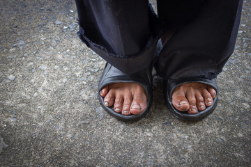 Dirty foot of a man stand on old concrete floor.