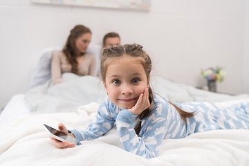 Daughter lying on bed with smartphone