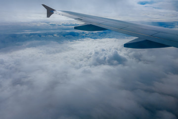 Wing of flying airplane in the clouds