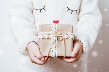 child's hands holding christmas gift box with bright red bow. close up.