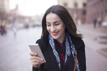 young attractive woman holding smartphone outdoors