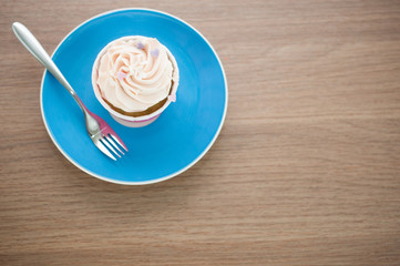 Top view of cupcake in blue plate with fork on wooden table