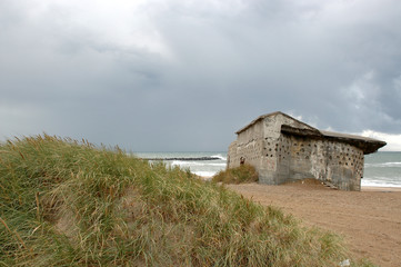 Obraz premium Remains of the Atlantic Wall at the beach of Thyboroen in Denmark. Built during WW2 the bunkers still stand visible and illustrates the former defense line.