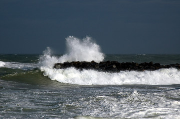 Dark skies in the background announce the arriving storm, the waves hitting the groynes are already harsh.