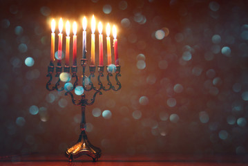 ewish holiday Hanukkah background with traditional spinnig top, menorah (traditional candelabra) and burning candles