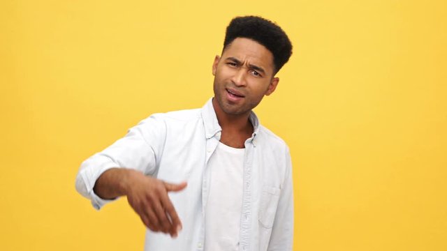 Serious african man in shirt conflicts with somebody over yellow background