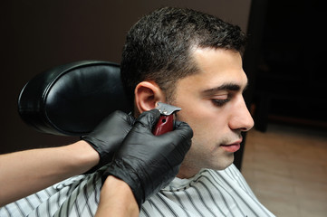 A man in a men's barber shop shaved his beard and creates a hairstyle