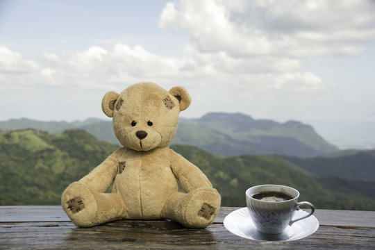 Teddy Bear sitting on a wooden floor with morning coffee