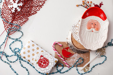 Christmas composition with decorations, gifts, tableware, candle, lace, cotton, tree, snow, glitter, letter balloons and the figure of Santa Claus. Top view