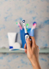 Electric toothbrush in hand on blue