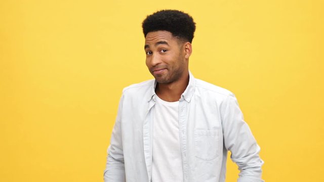 Young african man in shirt calls someone crazy over yellow background
