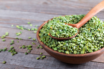 Bowl of green split peas on wooden background