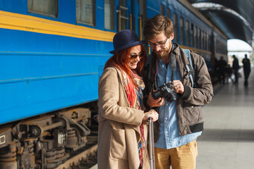 Portrait of young travelling couple looking at the photos. Tourism concept