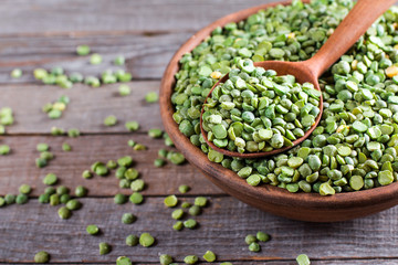 Green split peas in bowl and wooden spoon
