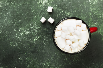 Cup of hot chocolate with marshmallow for Christmas on a green background. Top view, copy space