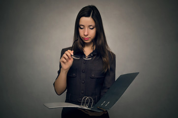 Young woman holding in hands document folder and searching some information within. Office paper work. Secretary woman.