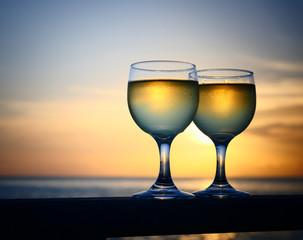 Romantic luxury evening on cruise yacht with winery setting. Glasses, white wine and tropical sunset with sea background. Vacation relax time on the sea with Two glasses of white wine. Maldives island