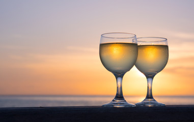 Romantic luxury evening on cruise yacht with winery setting. Glasses, white wine and tropical sunset with sea background. Vacation relax time on the sea with Two glasses of white wine. Maldives island