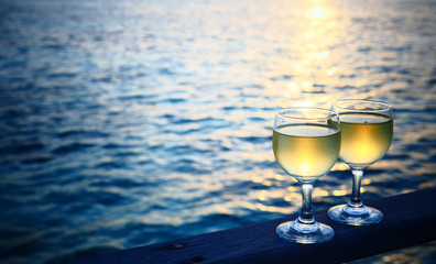 Romantic luxury evening on cruise yacht with winery setting. Glasses, white wine and tropical sunset with sea background. Vacation relax time on the sea with Two glasses of white wine. Maldives island