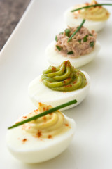 Variety of stuffed eggs with avocado and tuna  on wooden table