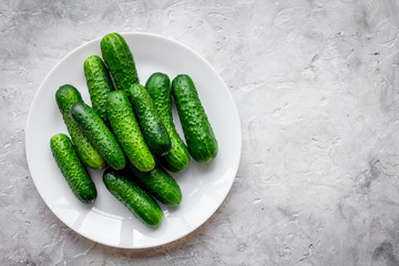 Fresh cucumbers on plate on grey background top view copyspace