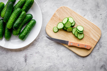 Cut fresh cucumbers on cutting board. Grey background top view copyspace