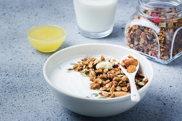 Homemade coconut oil honey almond granola and  yogurt on dark concrete background. Selective focus, copy space.