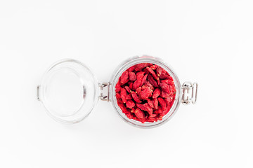 Dried goji berries in glass jar on white background top view copyspace