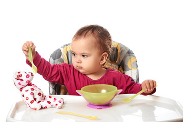 little child eats with spoon sitting at table with fruits isolated