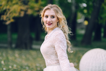 Happy, smiling bride with curly blonde hair. Portrait of beautiful girl on green nature background. Close-up