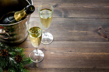 Champagne for celebrate new year. Glasses, bottle in bucket, spruce branch on wooden background copyspace