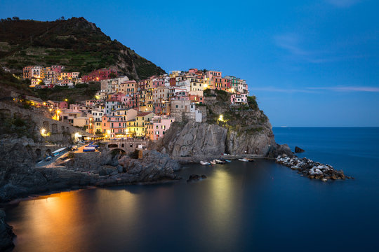 A long exposure at blue hour as the lights come on in the colourful town of Manarola, Cinque Terre, Liguria