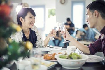 Asian young couple enjoying a romantic dinner  evening drinks while sitting at the dinning table on the kitchen together,soft focus