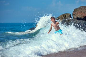 Cute Caucasian boy in sea waves.