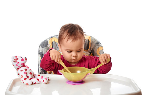 little child eats with spoon sitting at table with fruits isolated