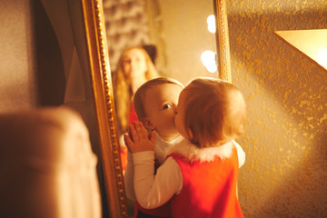 little girl kisses herself in the mirror - obrazy, fototapety, plakaty