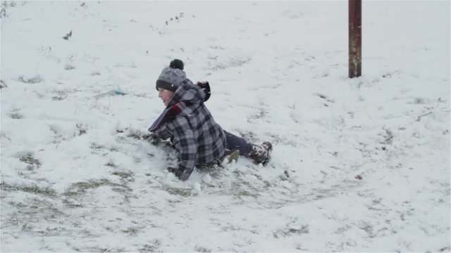 boy rides on the back of the snow/in the winter, in the snow, descend from the mountain in the buttocks