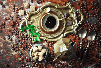 Black coffee in a cup on the table in a composition with coffee accessories on an old background