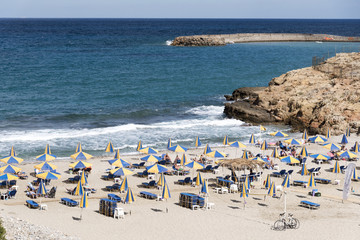 Beach and sunshades on the Cretan seaside resort of Sisi close to Malia, Crete, Greece. October 2017