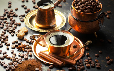 Black coffee in a cup on the table in a composition with coffee accessories on an old background